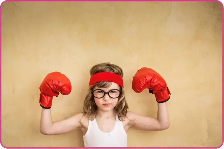 A child wearing boxing gloves, a vest, headband and glasses posing in a strongman style
